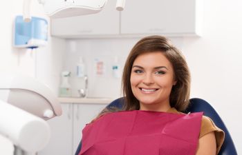 A smiling woman sitting in a dental chair.