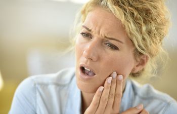 A woman with a toothache touching the painful jaw