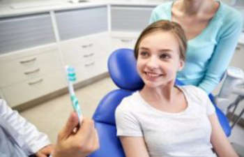 A young girl is sitting in a dentist's chair.