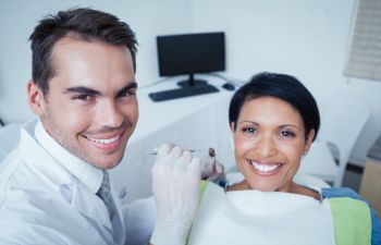 A male dentist and his satisfied female patient during an appointment.