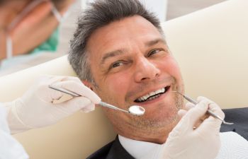 A man is getting his teeth examined by a dentist.