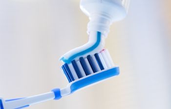 A toothbrush is being held by a blue and white toothbrush.