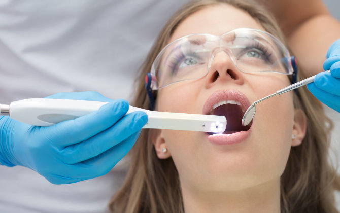 A woman during oral screening with intraoral camera.