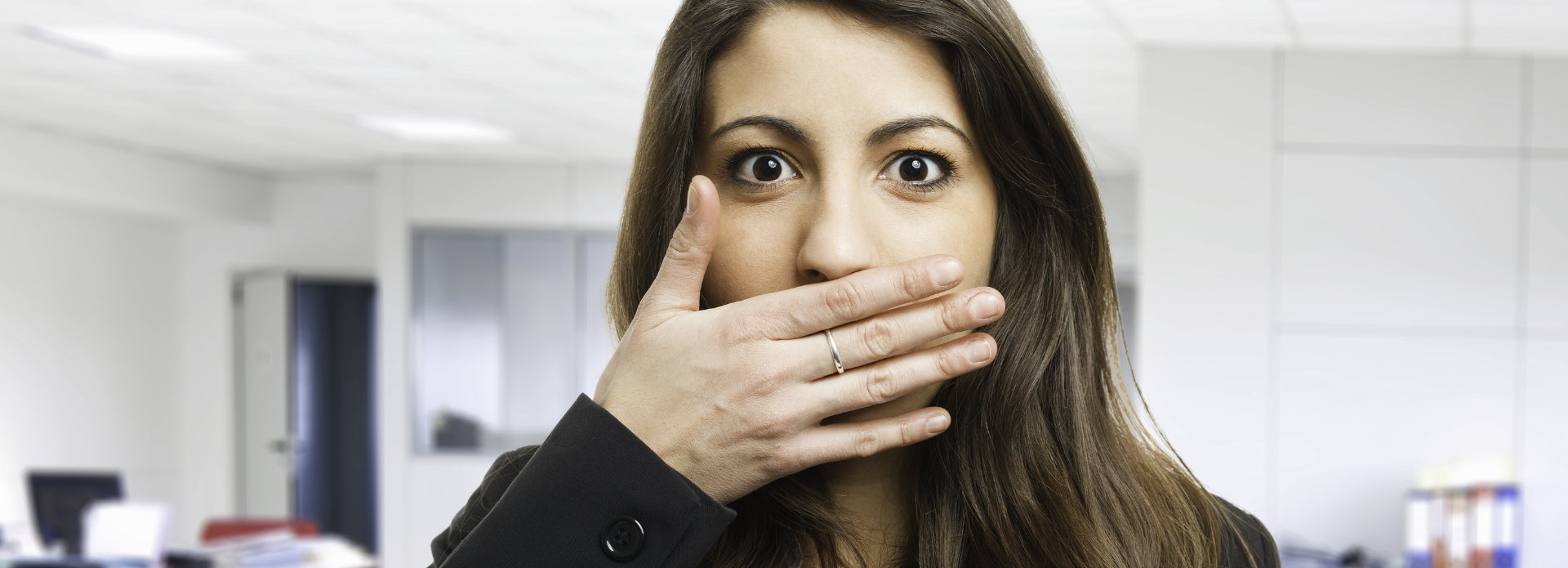 Concerned young woman covering her mouth with a hand due to halitosis.