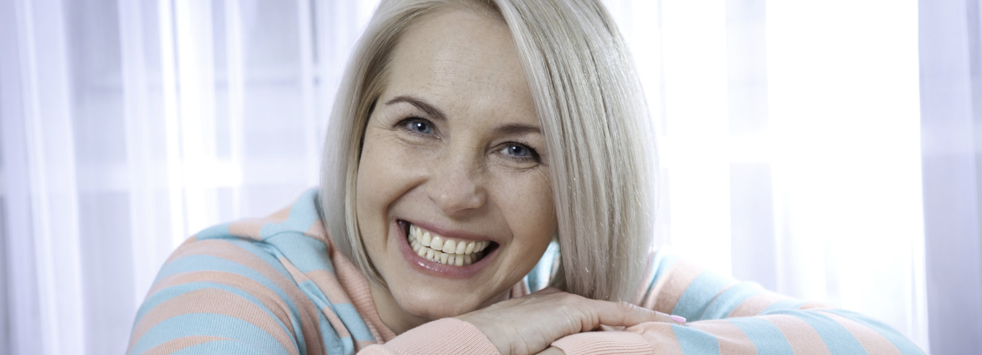 Joyful middle-aged woman showing nice teeth in her smile.