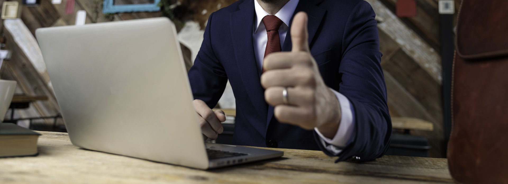 A businessman in front of his laptop showing his thumb up.