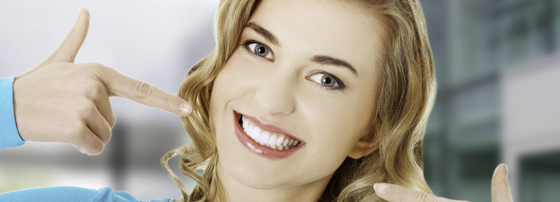 Happy young woman pointing at her whitened teeth.