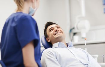 A man sitting in a dentist's chair and smiling.
