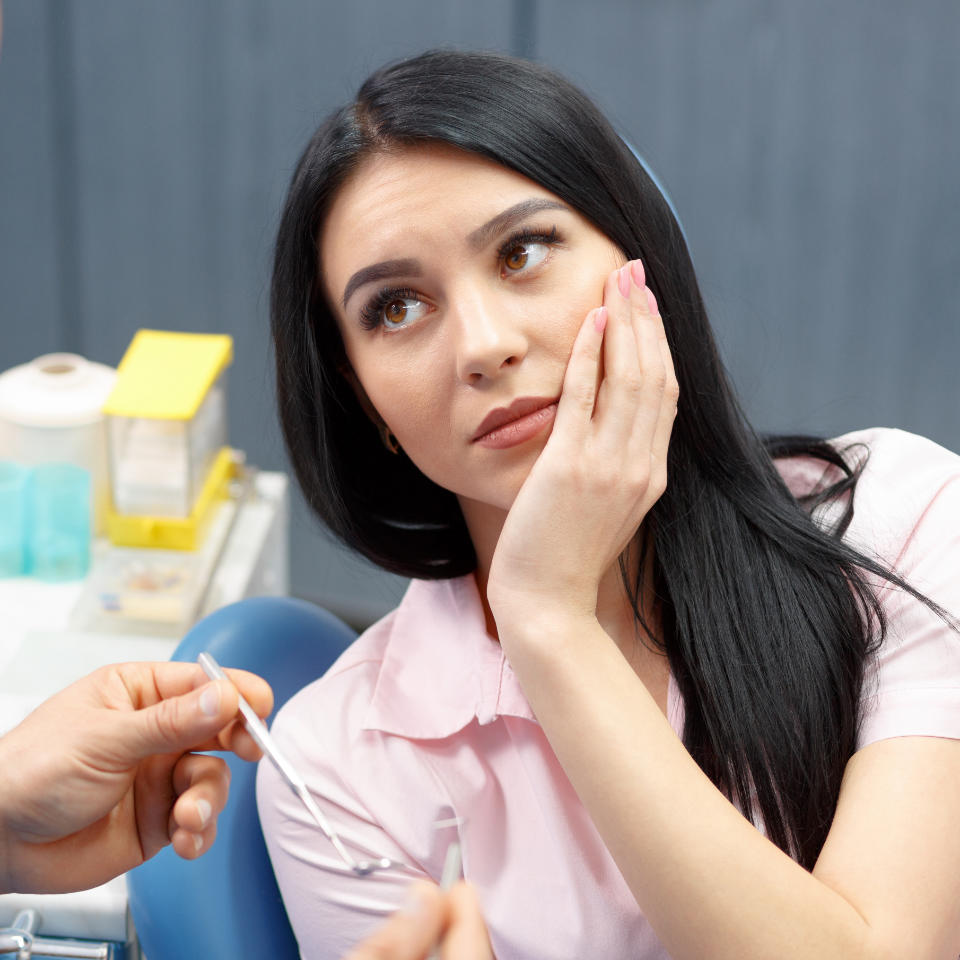 An emergency dentist consulting a woman with dental pain.
