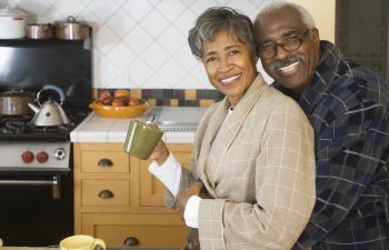 An older couple embracing in the kitchen.