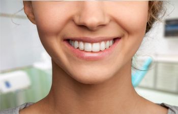 A woman smiles with her teeth in a dentist's office.