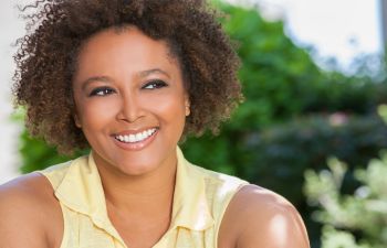 A woman with afro hair smiling outdoors.