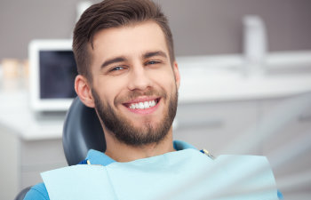 A man smiles while sitting in a dentist's chair.