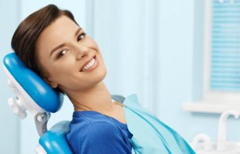 A woman smiling while sitting in a dental chair.