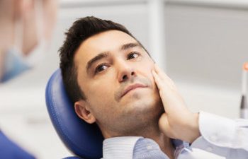 a man is sitting with a toothache in a dental chair