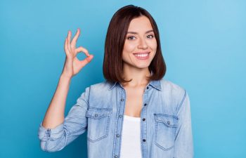 Happy woman with a perfect smile showing the OK sign with her fingers